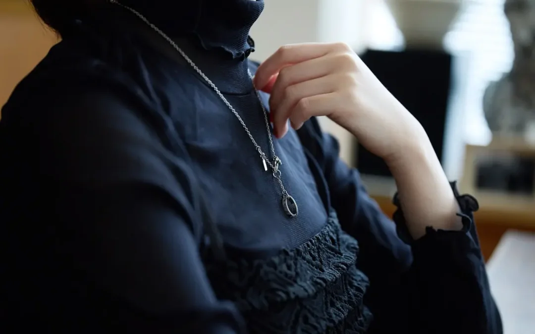 黒いブラウスに実物のシルバーネックレスを着けた女性